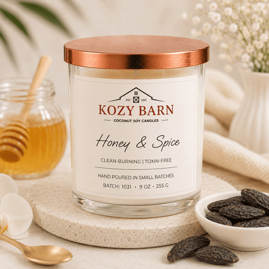 Kozy Barn candle labeled Honey and Spice sitting next to a container full of honey and a bowl of tonka beans.