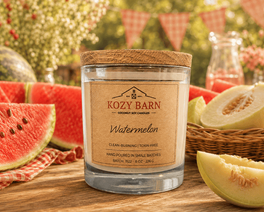 Kozy Barn candle labeled Watermelon sitting on wooden table next to fresh cut watermelon and honeydew melon. 
